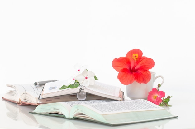 Libros con flores y taza de café en la mesa de mármol blanco