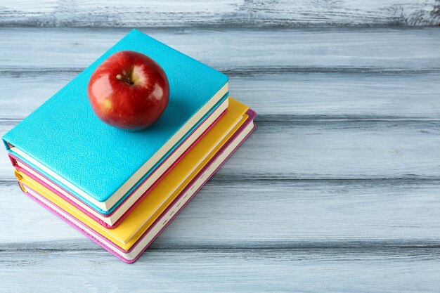 Libros y manzana sobre fondo de madera