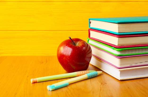 Libros y manzana sobre fondo de madera