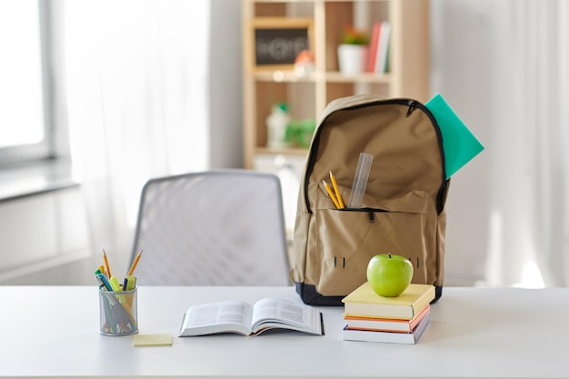 libros manzanas y artículos escolares en la mesa en casa