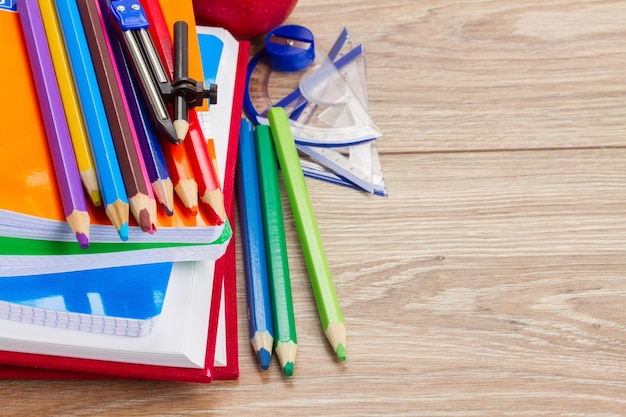 Libros con material escolar con espacio de copia en mesa de madera