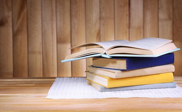 Foto libros en una mesa de madera sobre un fondo de pared de madera