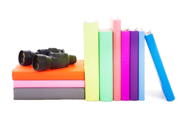 Foto libros multicolores y binoculares contra un fondo blanco