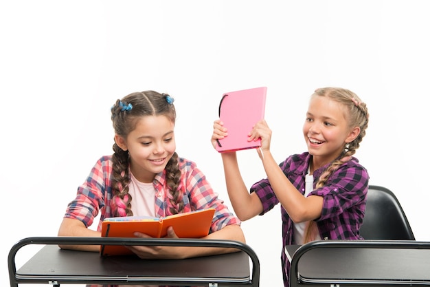 Los libros no son para golpear. Niña traviesa mimando a su compañera de clase por pelear en libros aislados en blanco. Niño juguetón jugando mientras libro de lectura de alumno pequeño. Libros educativos para alumnos.