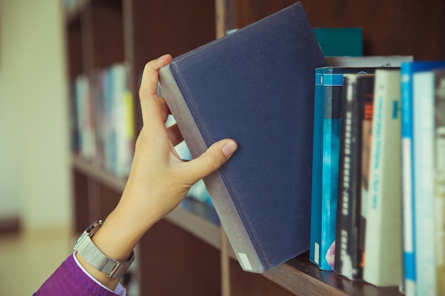 Libros seleccionados a mano en estanterías en el concepto library.education de regreso a la escuela