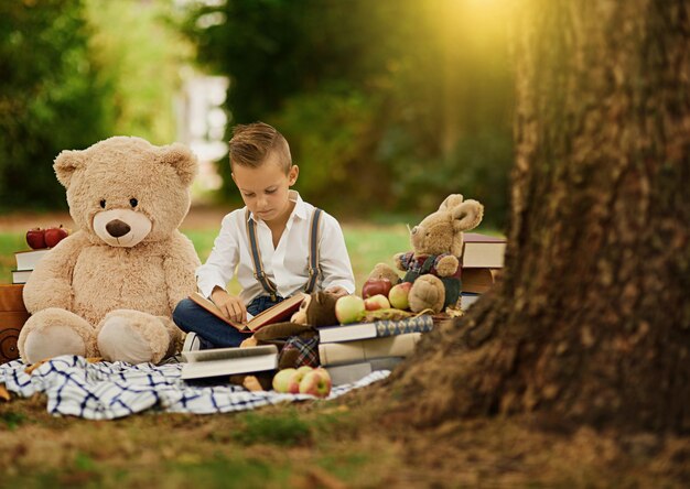 Los libros son la clave para el ancho mundo Captura de un niño leyendo a sus juguetes mientras está en el bosque