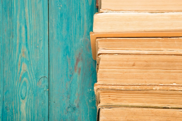 Libros de tapa dura viejos y usados o libros de texto en un escritorio de madera azul