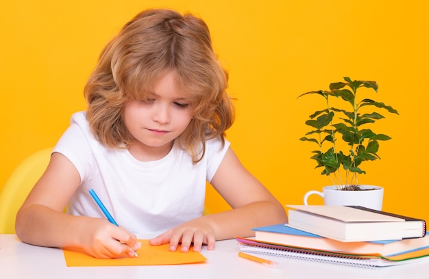 Lição de escrita infantil Aluno estudando em sala de aula na escola primária Garoto estudando na lição sobre fundo amarelo isolado Pequeno aluno aluno nerd inteligente Educação e aprendizagem