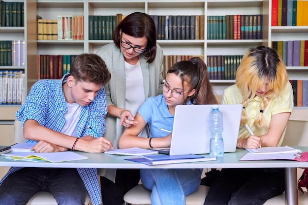 Lição no professor do ensino médio da biblioteca com grupo de adolescentes