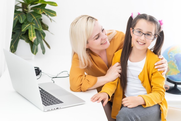 Lição privada. A professora tutora de uma jovem atenta ajuda a aluna a estudar a linguagem matemática, os erros corretos explicam o material de aprendizagem. A mãe sorridente ajuda a filha pequena com a tarefa em casa.