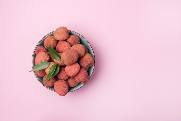 Lichi fresco y sabroso en un tazón sobre fondo rosa Vista superior Frutas sabrosas orgánicas horizontales