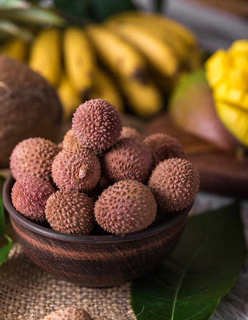 Lichi orgánico fresco en la cesta de bambú y fondo de madera vieja, enfoque selectivo de fondo borroso.