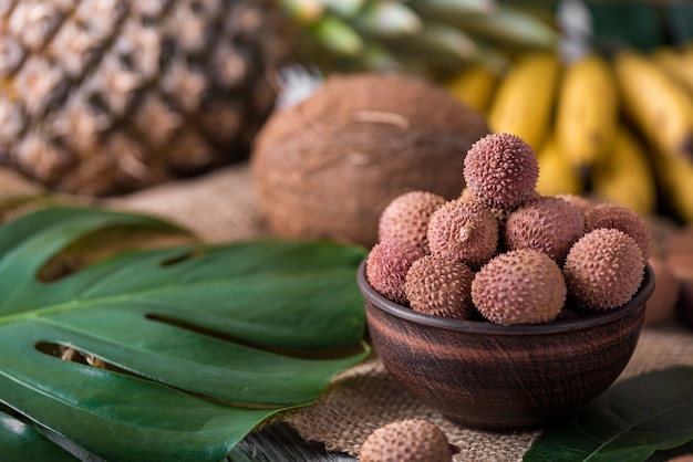 Lichi orgánico fresco en la cesta de bambú y fondo de madera vieja, enfoque selectivo de fondo borroso.