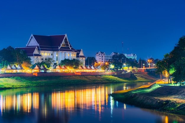 Licht auf dem Nan-Fluss mit Gericht Phitsanulok-Provinzgebäude am Nan-Fluss und dem Park nachts in Phitsanulok, Thailand.
