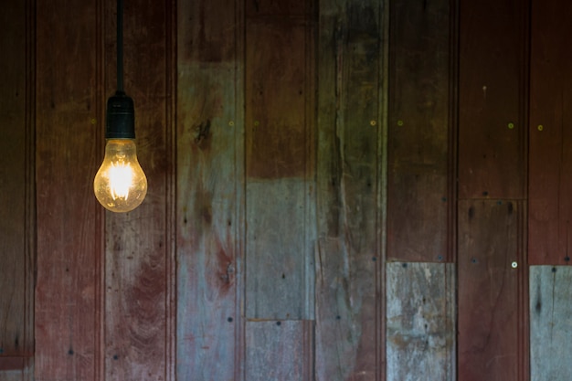 Licht von der Glühlampe der Weinlese mit altem hölzernem Wandhintergrund, Bild mit Kopienraum.