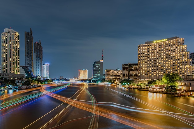 Lichtspuren auf dem Fluss inmitten von Gebäuden gegen den Himmel in der Stadt bei Nacht