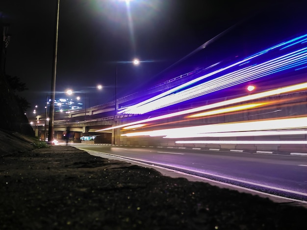 Lichtspuren über einer beleuchteten Straße in der Nacht
