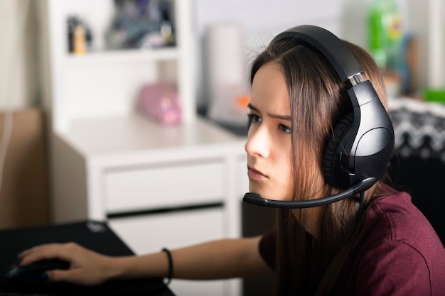 Lições de educação on-line aprendendo menina em casa na frente do monitor em fones de ouvido com microfone