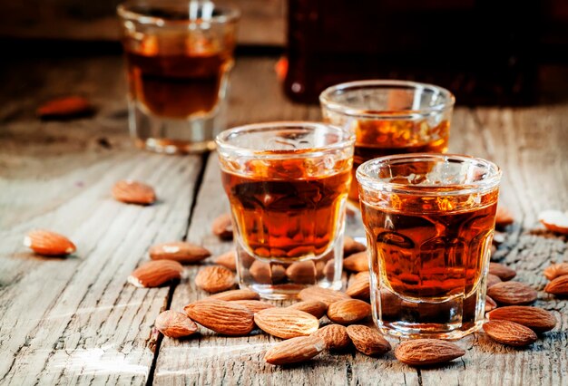 Licor de amaretto italiano con almendras secas en el antiguo enfoque selectivo de fondo de madera