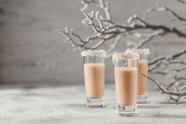 Foto licor de crema irlandesa o licor de café con corona de copos de coco encima de un vaso corto.