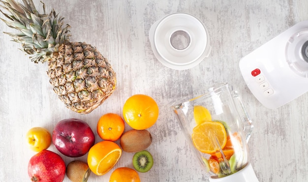 Licuadora blanca con frutas frescas sobre la mesa