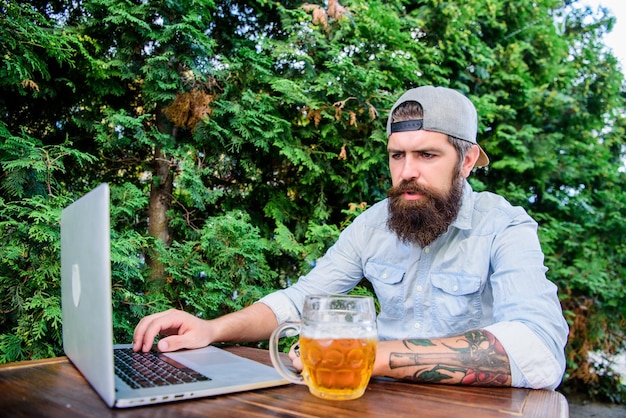 Lidando com a comunicação com o cliente Empresário com comunicação comercial por laptop Hipster trabalhando em um bar de cerveja com comunicação sem fio Usando ferramentas de comunicação on-line