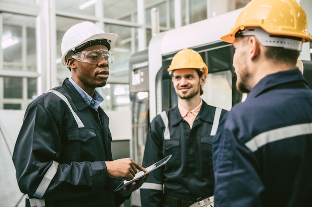 Líder da equipe de engenheiros negros africanos conversando com o grupo da faculdade de trabalhadores em equipe na fábrica moderna