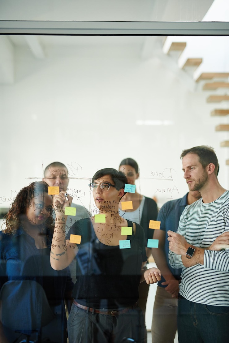 Foto líder de gerente ou chefe falando e planejando em um seminário ou apresentação de oficina com notas adesivas em uma sala de reuniões mulher de negócios discutindo e fazendo brainstorming com seus colegas e colegas de trabalho