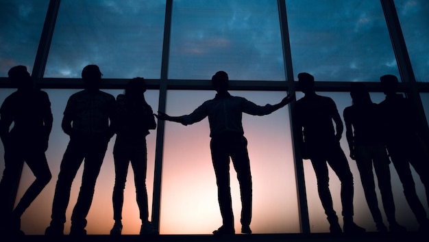 Foto líder y el equipo de negocios en el fondo de la ventana de la oficina