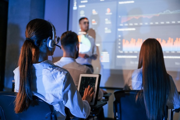 Foto líder masculino hablando con empleados que muestran el plan en el proyector en la oficina