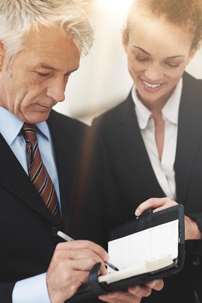 Foto líder mostrando e caderno para trabalhador no local de trabalho para negócios em empresa para estratégia mulher sorrindo e falando com o chefe no escritório feliz e profissional em roupas para trabalho ou trabalho