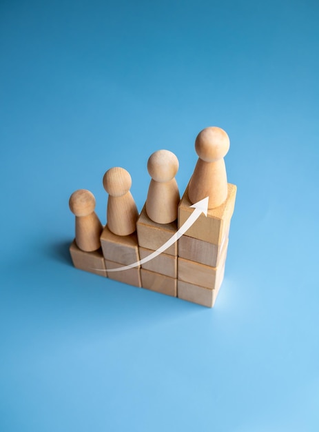 Liderança com o conceito de sucesso comercial seta ascendente e figuras de madeira em pé em um gráfico gráfico de crescimento etapas organizadas por blocos de cubo de madeira isolados na vista superior do estilo vertical de fundo azul