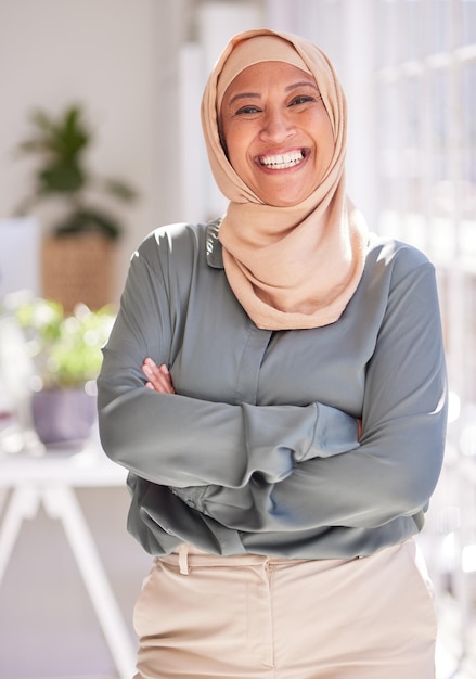 Liderança de sucesso e retrato de mulher muçulmana no escritório com sorriso de braços cruzados e profissional de empoderamento de confiança e trabalhadora feliz em pé no espaço de trabalho para inicialização de marketing