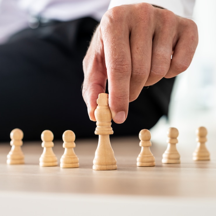 Foto liderança empresarial e conceito de poder - empresário segurando o rei da figura do xadrez na posição de poder na frente das figuras de peão.
