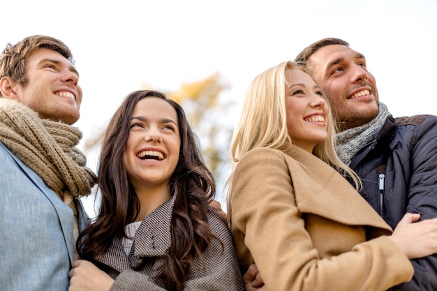 Liebe, Beziehung, Jahreszeit, Freundschaft und Personenkonzept - Gruppe lächelnder Männer und Frauen, die sich im Herbstpark umarmen