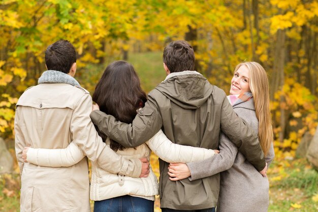 Foto liebe, beziehung, jahreszeit, freundschaft und personenkonzept - gruppe lächelnder männer und frauen, die sich im herbstpark umarmen