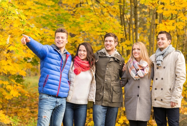 Liebe, Beziehung, Jahreszeit, Freundschaft und Personenkonzept - Gruppe lächelnder Männer und Frauen, die sich im Herbstpark umarmen