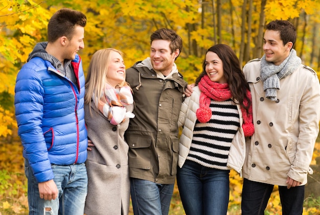 Liebe, Beziehung, Jahreszeit, Freundschaft und Personenkonzept - Gruppe lächelnder Männer und Frauen, die sich im Herbstpark umarmen