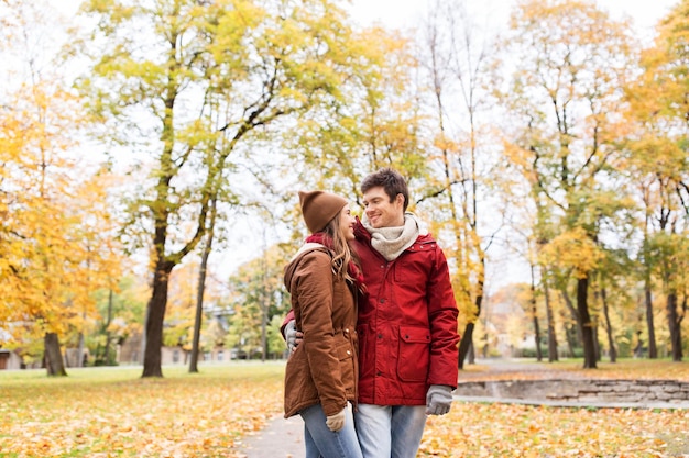 Liebe, Beziehungen, Jahreszeit und Menschenkonzept - glückliches junges Paar, das im Herbstpark spaziert