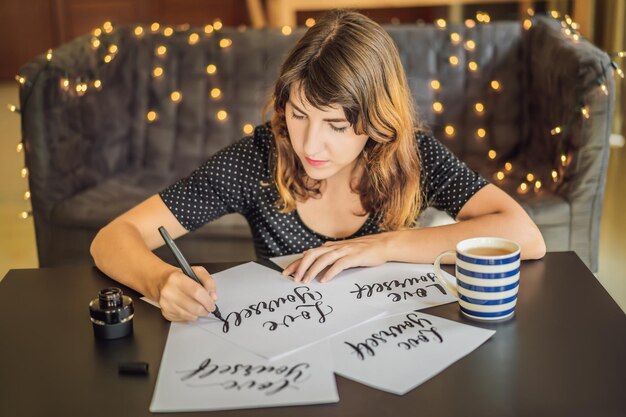 Liebe dich selbst Kalligraph Junge Frau schreibt Satz auf weißem Papier, das ornamental verzierte Buchstaben einschreibt Kalligraphie-Grafikdesign-Schriftzug Handschrifterstellungskonzept