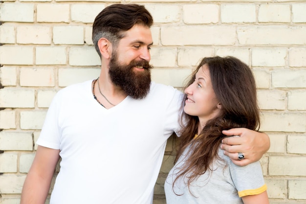 Liebe dich so sehr. Sinnliches verliebtes Paar auf Backsteinmauer. Bärtiger Mann, der hübsche Frau mit Liebe umarmt. Erotische Liebe von brutalem Hipster und sexy Frau.