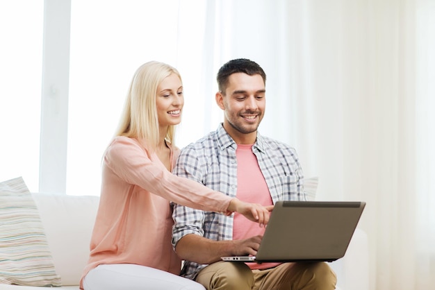 Liebe, Familie, Technologie, Internet und Glückskonzept - lächelndes glückliches Paar mit Laptop-Computer zu Hause