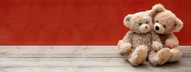 Liebe Freundschaft Konzept enge Umarmung Teddybären Paar auf Holzboden rote Wand Hintergrundbanner