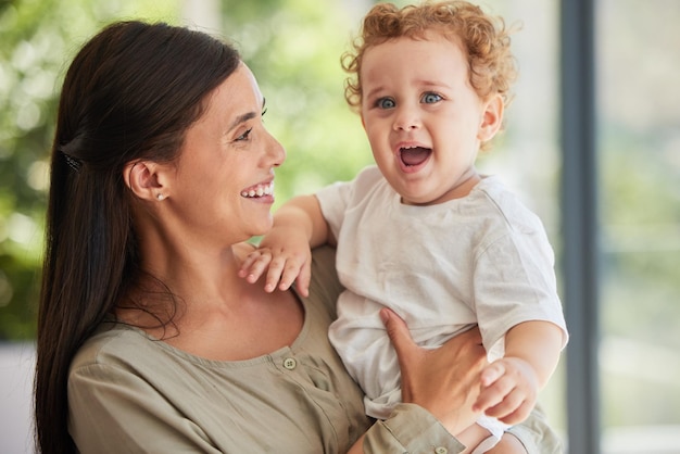 Liebe glücklich und Mutter mit Adoptionsbaby, die sich in einem gemischtrassigen Familienhaus entspannt, um sich zu verbinden Pflegeunterstützung und Freude der brasilianischen Mutter, die lächelt, während sie Pflegekind im Haus in den Armen hält