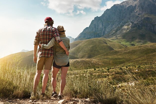 Liebe, inspiriert von der Schönheit der Natur Rückansicht eines jungen Paares, das eine bergige Aussicht in der Natur bewundert