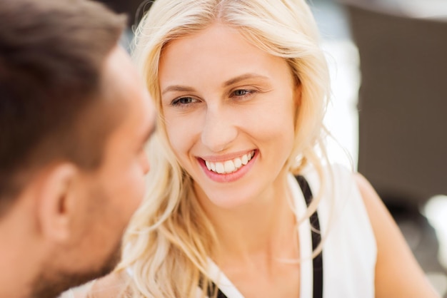 Liebe, Menschen, Kommunikation und Beziehungskonzept - glückliche Paargesichter im Restaurant, die einander anschauen