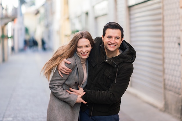 Liebe, Reisen, Tourismus, Beziehung und Dating-Konzept - romantisches glückliches Paar, das auf der Straße umarmt. St. Valentine Urlaub