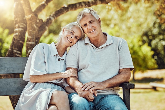 Liebe Ruhestand und Porträt eines Paares auf einer Parkbank mit einem Lächeln, entspannen Sie sich und verbinden Sie Zeit in der Natur zusammen. Romantik älterer Mann und Frau im Ruhestand im Garten glückliche Menschen und romantisches Sommerwochenende