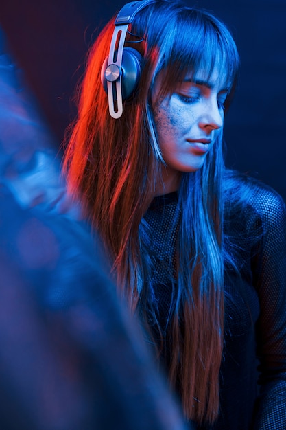 Liebe zum Detail. Studioaufnahme im dunklen Studio mit Neonlicht. Porträt des jungen Mädchens