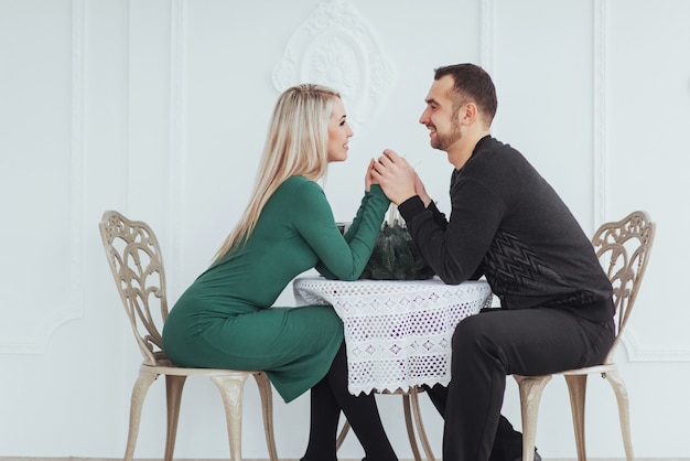 Lieben Sie, am Tischpaarmann und -frau mit Weingläsern auf Weiß im Restaurant zu sitzen. Valentinstag Abendessen